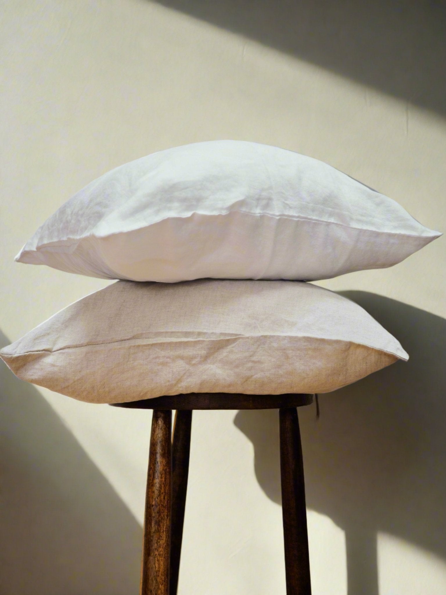 Linen Cushion Cover in White - TSL, two linen cushion covers placed on a stool